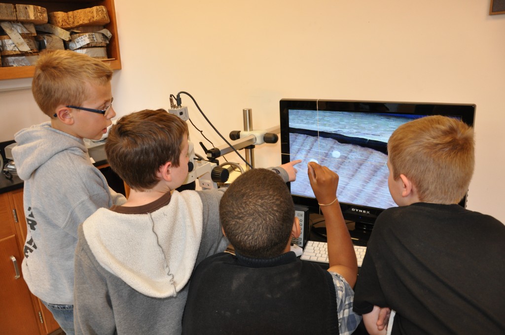 Cornerstone students look at a tree core under the microscope on a monitor display