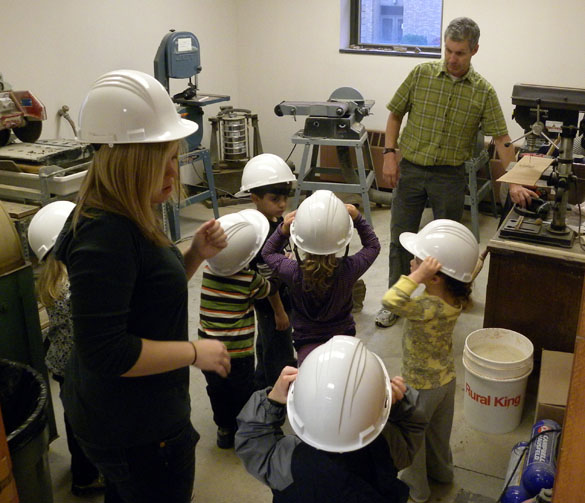 Children wearing hardhats in the preparation area (also the saw room in Scovel Hall)
